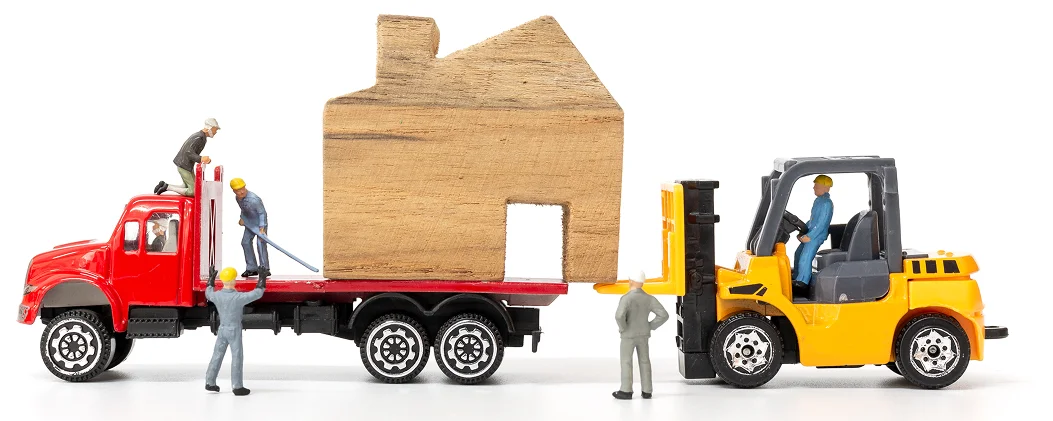 Minyatür işçiler, forklift yardımıyla ahşap bir evi kamyona yüklüyor, taşımacılık ve lojistik hizmetlerini temsil ediyor.